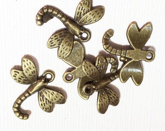 May include: Five antique bronze dragonfly charms with intricate details. Each charm features a different design, including a curled tail and delicate wings.