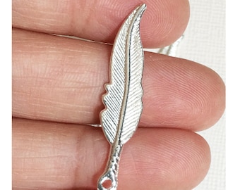 Op de afbeelding: Zilveren veerbedel met een gedetailleerd ontwerp. De bedel heeft een lus aan de onderkant om aan sieraden of andere knutselwerkjes te bevestigen.