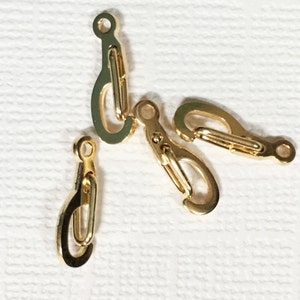 May include: Four gold-toned metal clasps or hooks. The clasps are small and have a simple design.