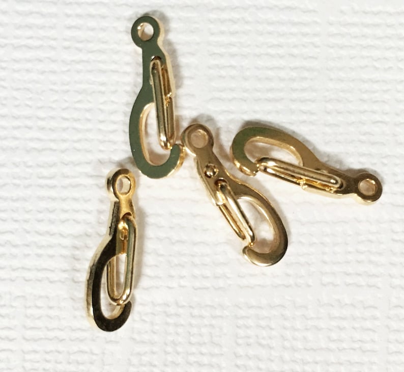 May include: Four gold-toned metal clasps or hooks. The clasps are small and have a simple design.