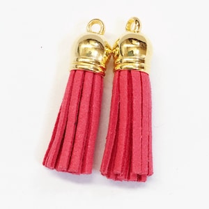 May include: Two red suede tassels with gold metal tops. The tassels are about 2 inches long.