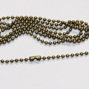 May include: A gold-toned metal chain with a lobster clasp. The chain is made of small, round beads.