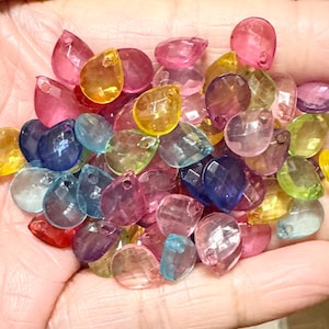 May include: A collection of colorful teardrop-shaped beads with a hole at the top. The beads are made of clear plastic and have a variety of colors, including pink, blue, green, yellow, and purple.