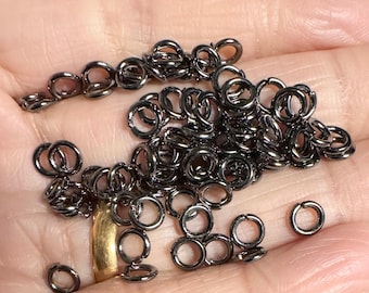 May include: A large pile of black jump rings. The rings are small and round, and they are all made of metal.