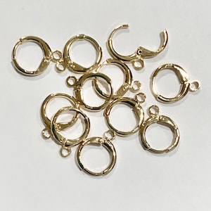 May include: A group of ten gold-toned earring hooks. The hooks are made of metal and have a circular shape with a small loop at the top.