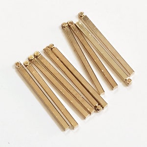 May include: A group of ten gold-colored metal bar connectors with a loop at one end. The connectors are arranged in a fan shape.