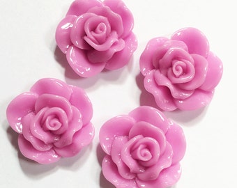 May include: Four pink plastic rose flower embellishments. The roses are 3D and have a glossy finish.