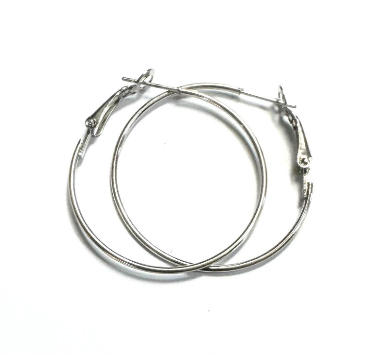 May include: A pair of silver hoop earrings with a hinged clasp.