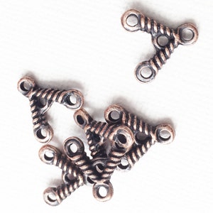 May include: A group of eight antique copper-toned metal connectors with a twisted rope design. Each connector has three loops.