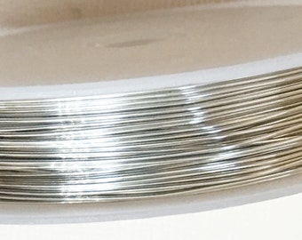 Puede incluir: Una bobina de alambre de color plateado, enrollada apretadamente alrededor de una bobina de plástico blanco.
