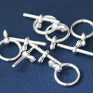 May include: Silver toggle clasps with a round ring and a straight bar. The clasps are designed for jewellery making and crafting.