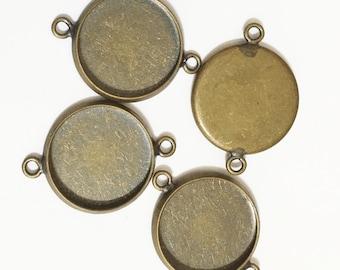 May include: Four antique gold-toned metal round pendant trays with a smooth, slightly textured surface and two jump rings on each.