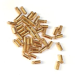 Peut inclure: Un tas de embouts métalliques dorés pour la fabrication de bijoux. Les embouts sont cylindriques avec une petite boule à chaque extrémité.