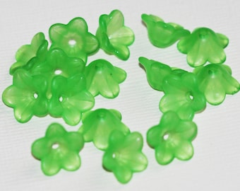 Op de afbeelding: Een verzameling van 15 groene plastic bloemvormige kralen. De kralen hebben vijf bloemblaadjes en een gat in het midden.