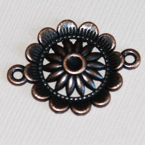 May include: A copper-coloured metal connector with a decorative flower design. The connector has two loops on the sides for attaching to other jewellery pieces.