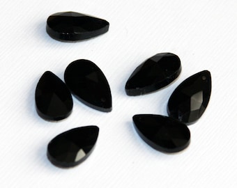 May include: Seven black teardrop-shaped crystal beads. The beads are faceted and have a glossy finish.