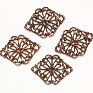 May include: Four copper-colored metal filigree embellishments in a diamond shape with a decorative floral design.