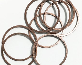 May include: A set of eight copper-colored metal rings, each with a hammered texture. The rings are stacked and overlapping, creating a decorative and abstract design.