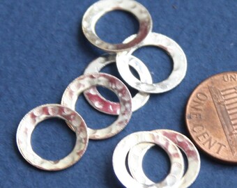 Peut inclure: Six anneaux en métal argenté avec une texture martelée. Les anneaux sont à peu près de la taille d'une pièce de un centime d'euro.
