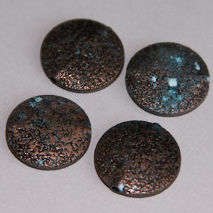 May include: Four round, flat, copper-colored beads with a textured surface. The beads have a speckled blue and white pattern.
