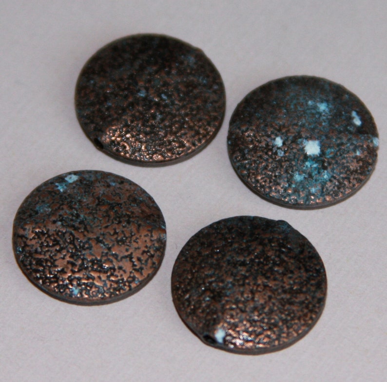 May include: Four round, flat, copper-colored beads with a textured surface. The beads have a speckled blue and white pattern.