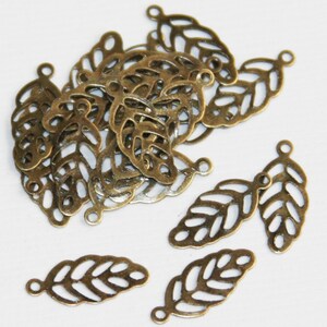 May include: A collection of antique bronze-colored metal leaf charms, each featuring a delicate filigree cutout design and a small circular loop at the top for attachment. These small, lightweight jewelry components are shaped like leaves.