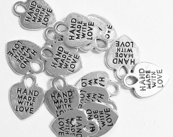 May include: A pile of silver heart-shaped charms with the text "Hand Made With Love" on them.
