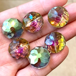May include: Six iridescent glass beads in shades of green, gold, and purple. The beads are faceted and have a round shape.
