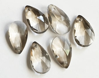 May include: Six clear teardrop-shaped crystal pendants with a faceted design. The pendants have a hole at the top for hanging.