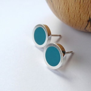 May include: A pair of silver stud earrings with teal blue circular inlays.