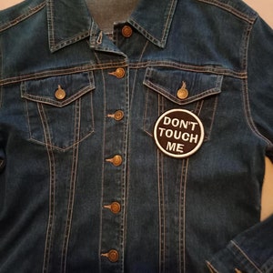 May include: A blue denim jacket with a black and white patch that says "Don't Touch Me".