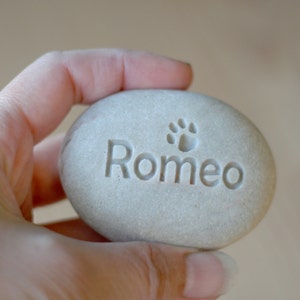 May include: A gray stone with the name "Romeo" engraved on it, along with a paw print.