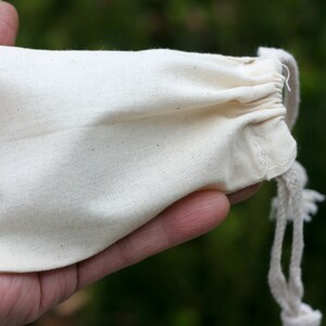 May include: A small, white cotton drawstring bag with a white cord.