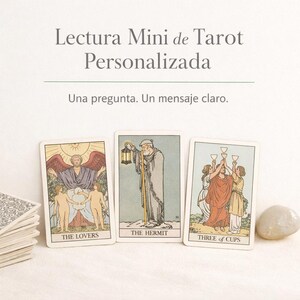 May include: Three tarot cards are displayed, featuring illustrations and titles: "The Lovers," "The Hermit," and "Three of Cups." The cards are arranged on a light surface, with a stack of cards and a stone visible.