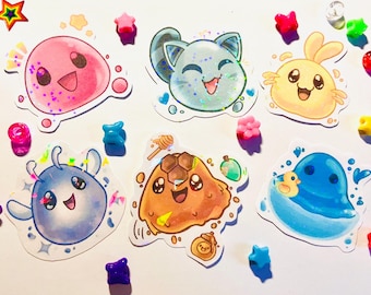 May include: A collection of colorful, cartoonish stickers featuring smiling, blob-like characters in pink, blue, yellow, and brown. Decorative star and gem-shaped embellishments surround the stickers, creating a playful and whimsical aesthetic.