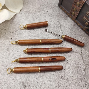 May include: Five wooden keychain tools with a gold accent. The tools have a small loop at the top for attaching to a keychain. One of the tools has the word "Papa" engraved on it.