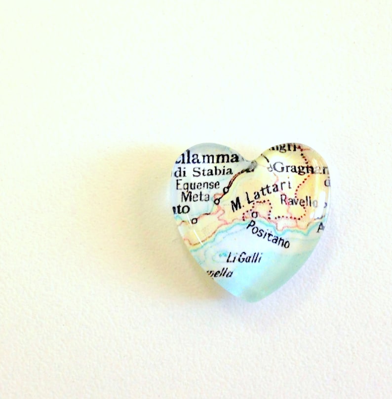 May include: A heart-shaped glass paperweight featuring a map of the Amalfi Coast, Italy. The map highlights the towns of Positano, Ravello, and Li Galli.