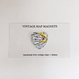 Puede incluir: Un im&aacute;n en forma de coraz&oacute;n con un mapa vintage de Islandia. El mapa muestra la ubicaci&oacute;n de Reikiavik, Akranes y otras ciudades. El im&aacute;n est&aacute; hecho a mano con mapas y atlas antiguos. "VINTAGE MAP MAGNETS" y "Handmade from vintage maps + atlases" est&aacute;n impresos en la tarjeta blanca detr&aacute;s del im&aacute;n.
