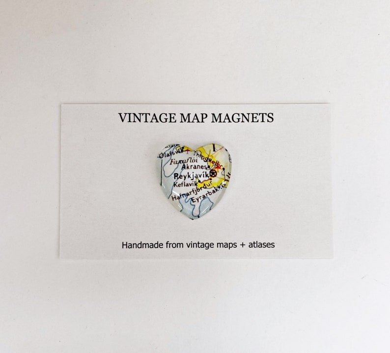 Puede incluir: Un im&aacute;n en forma de coraz&oacute;n con un mapa vintage de Islandia. El mapa muestra la ubicaci&oacute;n de Reikiavik, Akranes y otras ciudades. El im&aacute;n est&aacute; hecho a mano con mapas y atlas antiguos. "VINTAGE MAP MAGNETS" y "Handmade from vintage maps + atlases" est&aacute;n impresos en la tarjeta blanca detr&aacute;s del im&aacute;n.