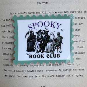 May include: A green and white sticker with a spooky book club theme. The sticker features a black and white illustration of a group of spooky characters, including a skeleton, a witch, a vampire, a ghost, and a mummy, all sitting around a table reading books. The text "SPOOKY BOOK CLUB" is printed in purple and white letters.