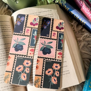 May include: Two bookmark designs featuring floral illustrations. The bookmarks are rectangular and have a dark background with a pink and orange floral design. The text on the bookmarks reads "35" and "ANEMONE".