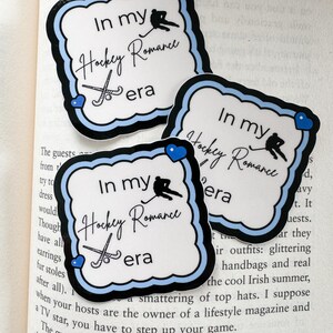 May include: Three stickers with a white background and a black and blue border. The stickers feature the text "In my Hockey Romance era" with hockey-themed graphics. Each sticker has a blue heart.