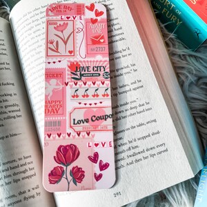 May include: A pink and red bookmark featuring a collage of vintage-style love-themed illustrations. The bookmark includes a variety of hearts, flowers, and text, such as "Love Day", "Love City", "Love Coupon", and "Happy Hearts Day".