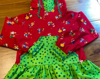 Puede incluir: Sudadera roja con capucha y falda verde de lunares. La sudadera tiene un estampado de osos y otras figuras pequeñas. La falda tiene un volante verde en la parte inferior.