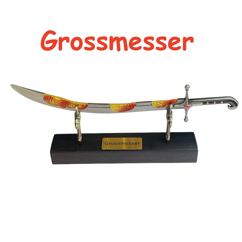 Op de afbeelding: Een decoratief zwaard met een gebogen lemmet, met gouden en rode accenten. Het zwaard wordt tentoongesteld op een zwarte houten standaard met een gouden naamplaatje met de tekst "Grossmesser". Het woord "Grossmesser" staat ook in het rood boven het zwaard.