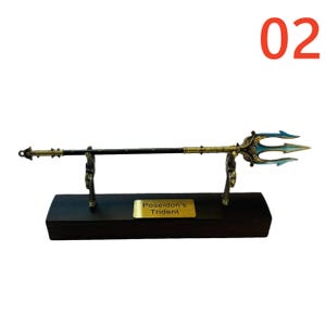 May include: A decorative trident with a black shaft and gold and teal accents, displayed on a wooden base. The trident is labeled "Poseidon's Trident" on a gold plaque. The number "02" is in the upper right corner.