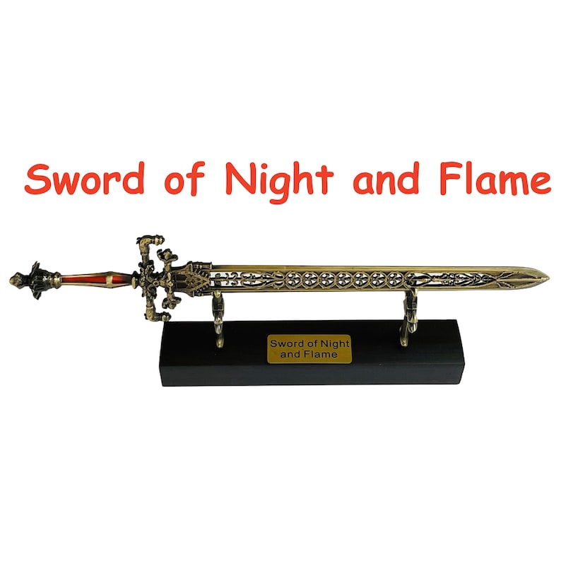 Op de afbeelding: Een decoratief zwaard met een bronzen afwerking, tentoongesteld op een zwarte standaard. Het zwaard heeft ingewikkelde details en een rode handgreep. De tekst "Sword of Night and Flame" is zichtbaar boven het zwaard.