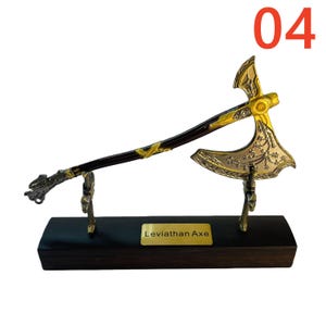May include: A decorative Leviathan Axe replica, featuring a gold-colored blade and accents, a dark brown handle, and a black wooden base. The axe is displayed on a stand with the number "04" in the upper right corner.