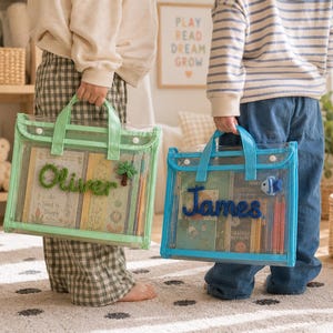 May include: Two rectangular clear plastic tote bags with handles and snap closures. One bag features green trim and the name Oliver in green yarn with a palm tree accent. The other bag has blue trim and the name James in blue yarn with a fish accent.