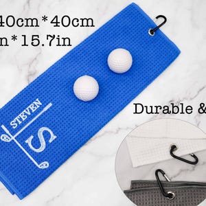 Puede incluir: Toalla de golf azul con el texto "STEVEN" bordado en blanco y un dise&ntilde;o de palo de golf. La toalla mide 40 cm por 40 cm y tiene dos bolas de golf blancas en la parte superior. El texto "Durable & Hard" es visible en el fondo.